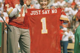 Washington Redskins injured starting quarterback Doug Wiliams stands behind First Lady Nancy Reagan holds a jersey presented to her by Williams prior to the start of game against the New York Giants at RFK Stadium in Washington, D.C., Oct. 2, 1988. The ceremony marked the  Redskins' salute to the First Ladys' "Just Say No' anti-drug campaign. (AP Photo/Doug Mills)