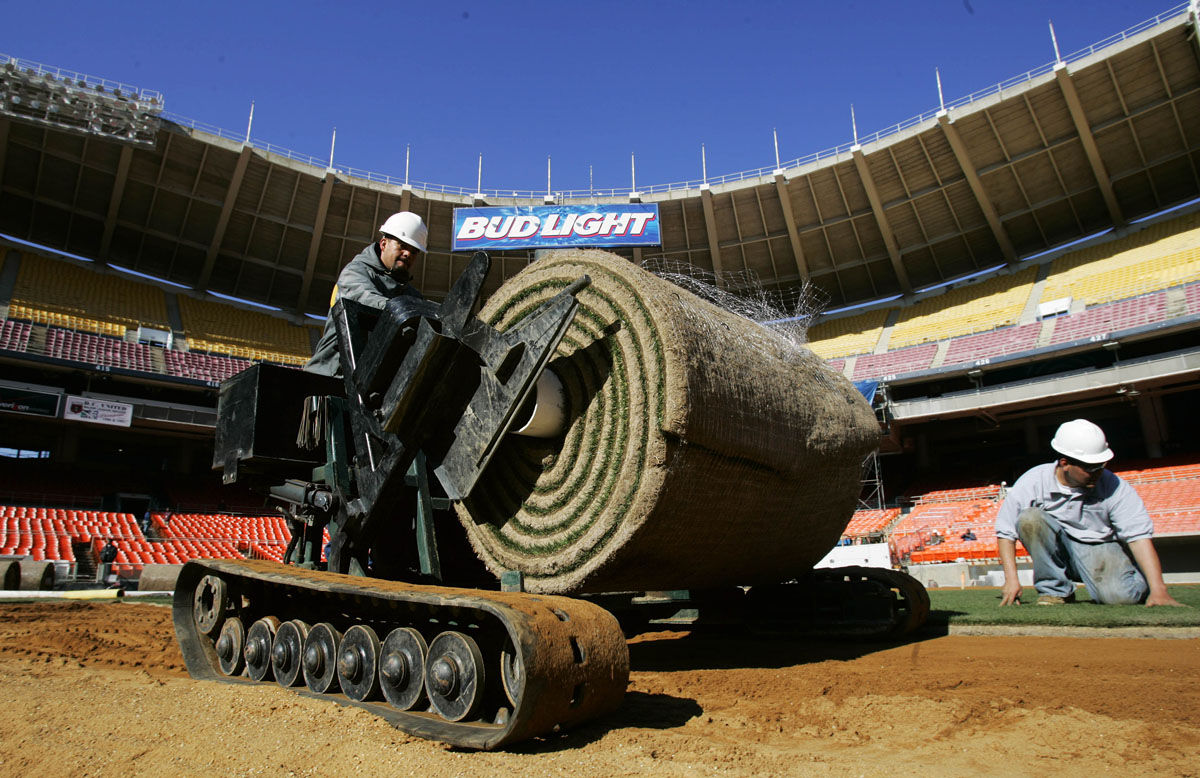 Gabriel Macedo, left, operates a lift as workers install turf on the Washington Nationals' home field at RFK Memorial Stadium, Monday, March 14, 2005, in Washington.  The playing field will have 111,000 square feet of sand-based hybrid Bermuda grass over-seeded with perennial rye grass.  Worker on the right is Raul Reyes. The first game is April 3 (AP Photo/Manuel Balce Ceneta)