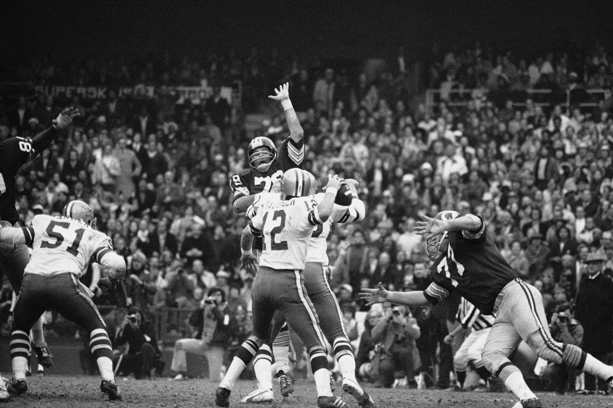 Dallas Cowboys quarterback Roger Staubach rears back to pass 22 yards to Ron Sellers (88) on a third down play late in the second quarter, Dec. 31, 1972. Ron McDole, a defensive end for the Redskins (79) leaps high to early to block the pass during the National Football Conference Championship Game in Washington. (AP Photo)