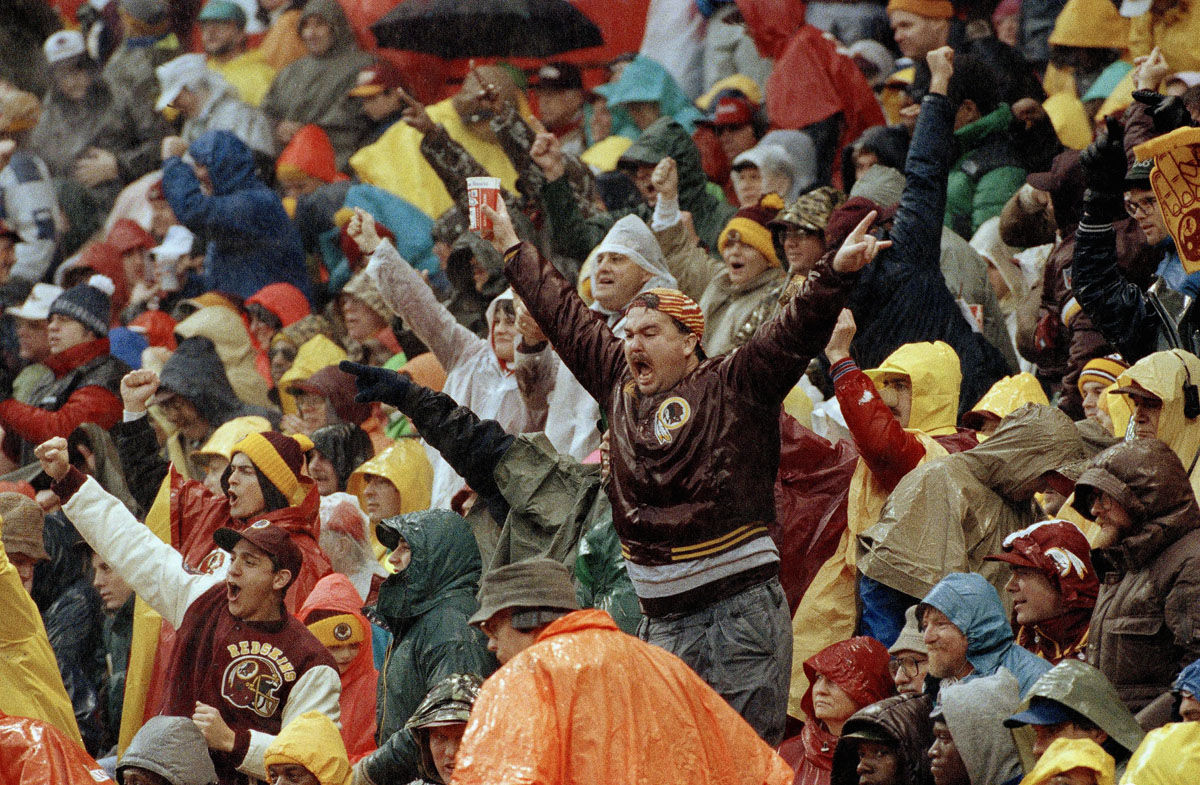 Washington Redskins fans cheer in the rain during NFL Divisional playoff game against the Atlanta Falcons, Jan. 4, 1992, at RFK Stadium in Washington, D.C. The Redskins won 24-7. (AP Photo/Doug Mills)
