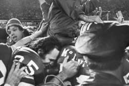 Redskins head coach George Allen is carried from the field by his player after they beat the Dallas cowboys 26-3 in the National Football Conference Championship game, Dec. 31, 1972 in Washington. Before Allen was carried across the field a fan, left, reached up and snatched his cap. (AP Photo)