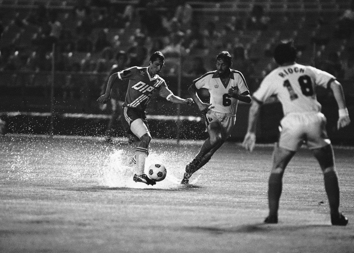 Washington Diplomats? Johan Cruyff (14), left, carries the ball past Seattle Sounders? Roy Greaves during North American Soccer League action at night on Wednesday, July 16, 1980 in Washington. Playing under sporadic thundershowers and a record-breaking 102 degree temperature, the Diplomats won it 3-2. (AP Photo/Peter Cullen)