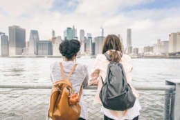 Two women looking at New York skyline - Multiethnic girl leaning on a railing and watching at cityscape