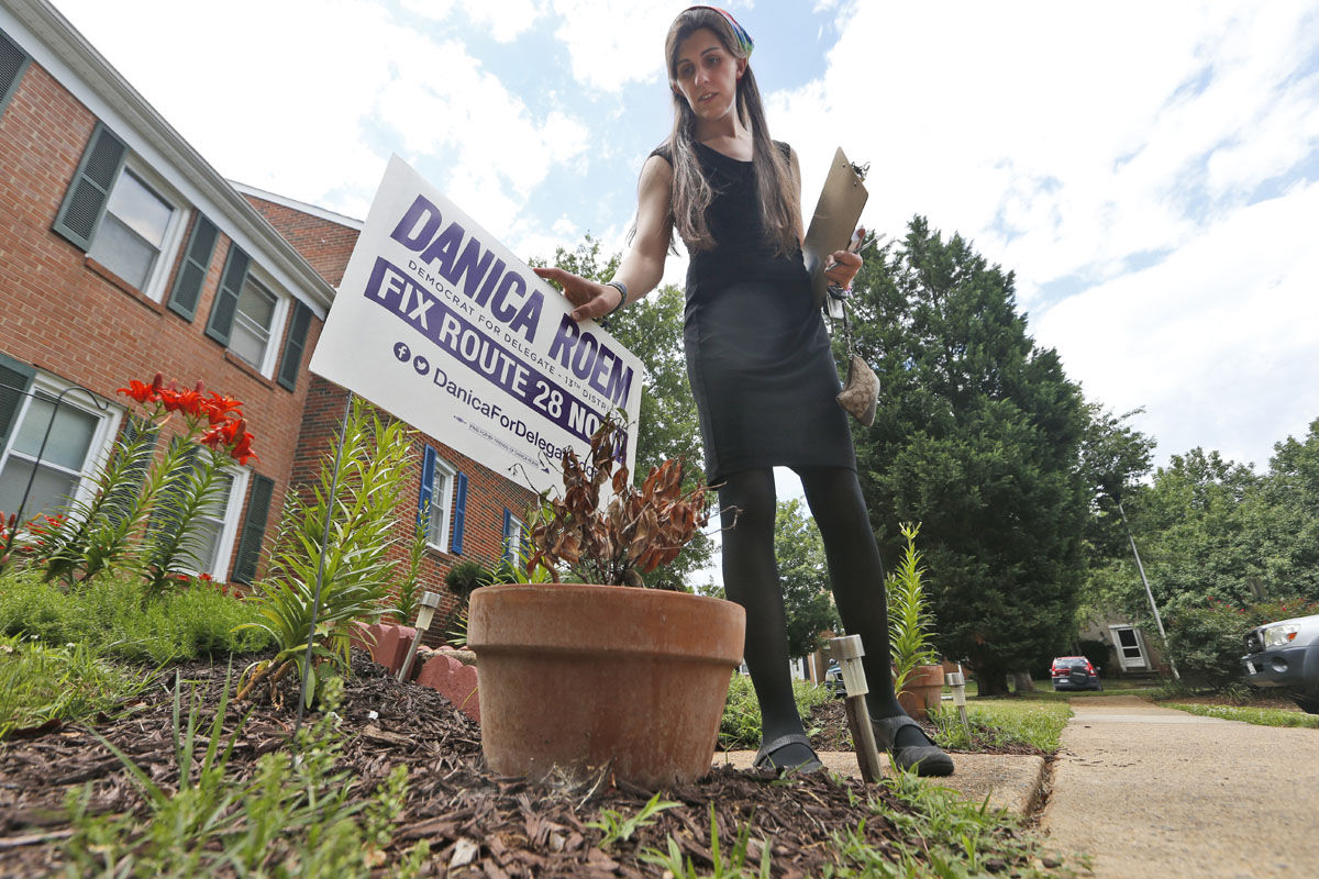 Democratic nominee for the House of Delegates 13th district seat, Danica Roem, places a campaign sign as she canvasses a neighborhood Wednesday, June 21, 2017, in Manassas, Va. Roem is running against Del. Bob Marshall in the 13th House of Delegates District. (AP Photo/Steve Helber)