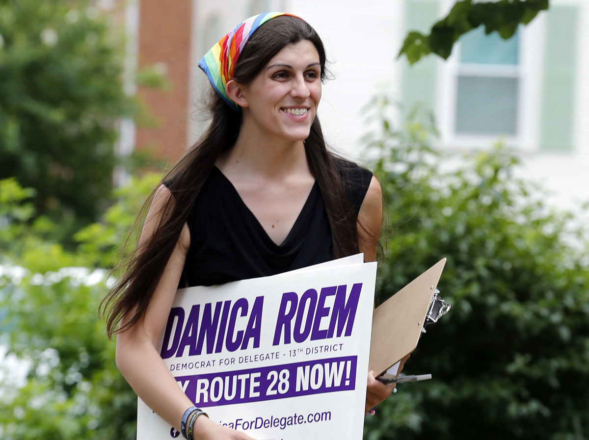 FILE - In this June 21, 2017, file photo, Democratic nominee for the House of Delegates 13th district seat Danica Roem brings campaign signs as she greets voters while canvasing a neighborhood in Manassas, Va. Roem, a former journalist, is challenging longtime incumbent Bob Marshall. If elected, Roem would be the stateâ€™s first transgender representative. (AP Photo/Steve Helber, File)