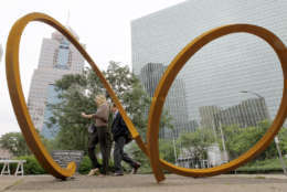 A couple of passers-by walk past the sculpture by Dee Briggs called "Two Rings - Eight Foot" installed on a median along Liberty Ave. in downtown Pittsburgh as the Three Rivers Arts Festival opens on Friday, June 1, 2012. The annual festival featuring paintings, photography, sculpture, crafts, performance and other various arts is scheduled to run through June 10, 2012. (AP Photo/Keith Srakocic)