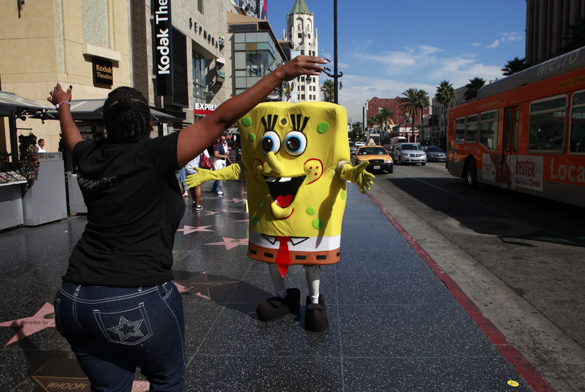 Bernard Golden, center, dressed as Spongebob Squarepants, gets a hug from Deanna Jones, of Claremont, Calif., in the Hollywood section of Los Angeles, Wednesday, Sept. 29, 2010. (AP Photo/Jae C. Hong)