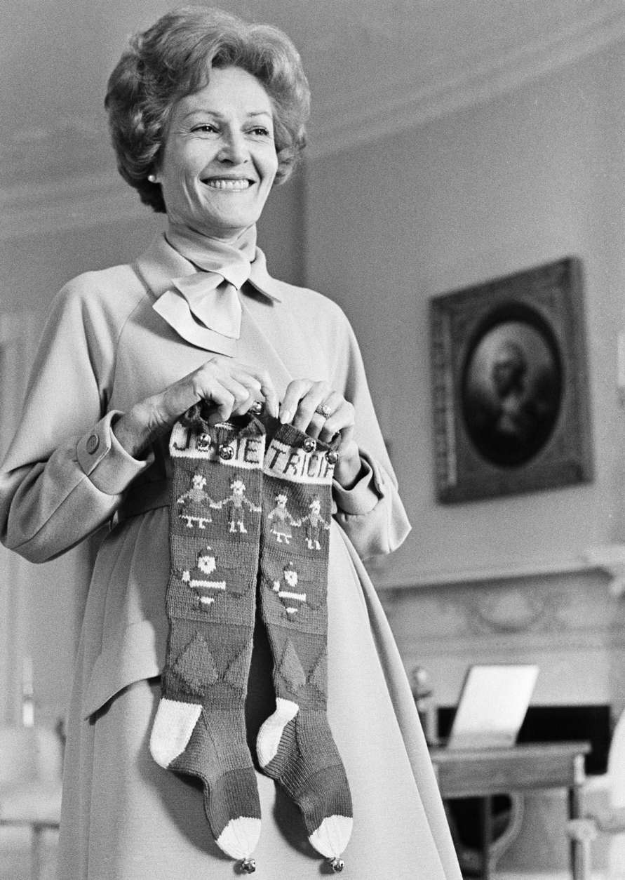 First lady Pat Nixon holds stockings carrying the names of daughters Julie and Tricia as she helps with pre-Christmas decorating at the White House in Washington, Dec. 6, 1969. The stockings have hung on the Nixon mantle each Christmas since the girls were little. (AP Photo/Henry Burroughs)