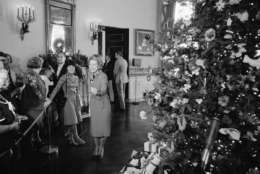 First lady Betty Ford, center left, demonstrates her skiing form for unidentified reporters gathered in the Blue Room of the White House, Dec. 10, 1976. Mrs. Ford gave the reporters a showing of the 1976 White House Christmas tree, right. (AP Photo/Charles Tasnadi)
