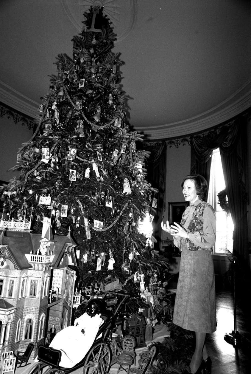 First Lady Rosalynn Carter stands beside the White House Christmas tree Tuesday, December 12, 1978,  during a preview for reporters.  The tree is decorated with antique toys, dolls, and miniature furniture from the collections of the Margaret Woodbury Strong Museum in Rochester, N.Y.  (AP Photo/Barry Thumma)