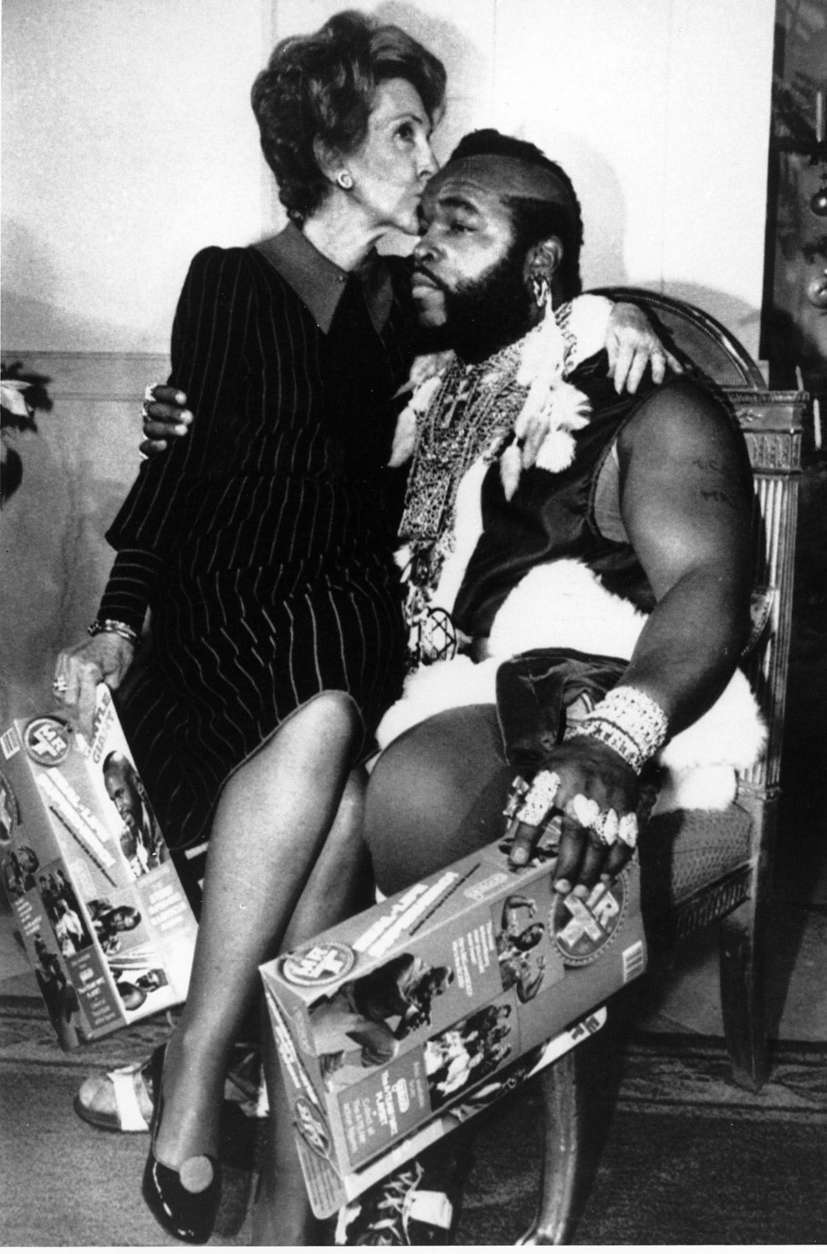 First lady Nancy Reagan sits on the knee of television personality Mr. T, dressed as Santa Claus, as he joined her for a preview of the White House Christmas decor on Dec. 12, 1983 in Washington, D.C. (AP Photo/Ira Schwarz)