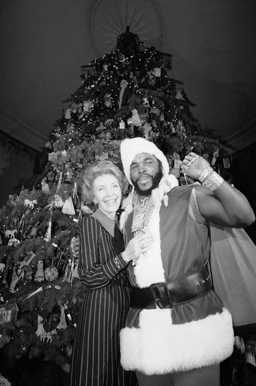 First lady Nancy Reagan enlists the help of television's Mr. T during a Christmas tour of the White House for the media on Monday, Dec. 13, 1983 in Washington. The two are shown in front of the executive mansion's official Christmas tree, a 20-foot Noble fir containing about 2,000 ornaments and several thousand lights, in the Blue Room. (AP Photo/Ira Schwarz)