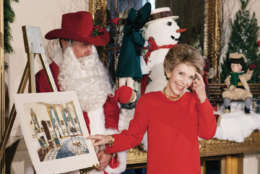 First Lady Nancy Reagan and Larry Hagman, who plays J.R. Ewing on the television series "Dallas," conduct a press tour of a Christmas decorated White House, Monday, Dec. 9, 1985 in Washington. An enlarged version of the Reagan Christmas card sits at left. (AP Photo/Bob Daugherty)