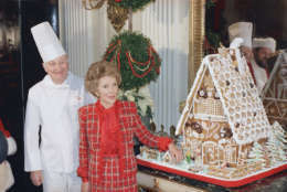 First Lady Nancy Reagan, second from left, touches a gingerbread Rex, her pet dog, who sits next to a little doghouse next to the big White House gingerbread house, Monday, Dec. 15, 1987, Washington, D.C. Mrs. Reagan showed off the house during a tour of the White House Christmas decorations. Reflections of Dom DeLuise, dressed as Santa, and the White House chef can be seen in the mirror. The chef is unidentified. (AP Photo/Barry Thumma)