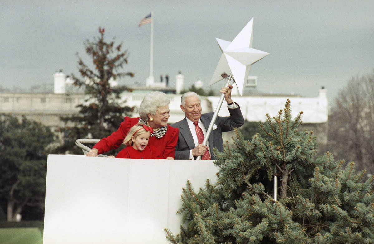 First Lady Barbara Bush and granddaughter Marshall Bush join Joseph Riley as they place the main ornament atop the National Christmas Tree on the Ellipse in Washington Monday, Nov. 27, 1989 in Washington. Mrs. Bush have participated in the topping of the tree every year since 1981, but this was the first time a first lady has ever participated in the event. Riley is president of the Christmas Pageant of Peace Inc. (AP Photo/John Duricka)