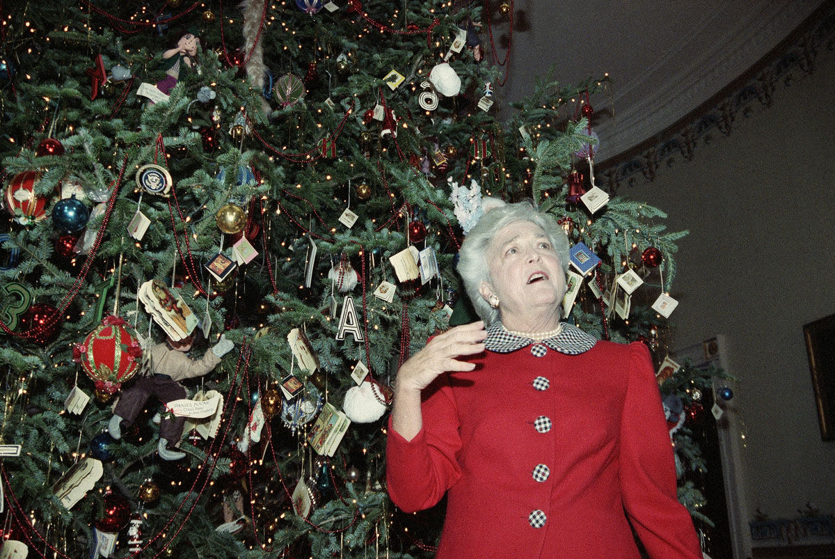 First lady Barbara Bush shows off the White House Christmas tree in the Blue Room, Monday Dec. 12, 1989, in Washington. The first lady was conducting a tour for members of the press. (AP Photo/Dennis Cook)
