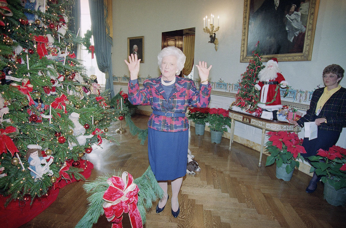 First Lady Barbara Bush, center, gestures at the White House while showing off the Christmas decorations, Monday, Dec. 8, 1992, Washington, D.C. Mrs. Bush accused the press corps on Monday of being humorless, making up anonymous sources and falsely depicting her husband as despondent after his election defeat.  After having her say she remarked, "I feel better for that." The woman on the right is unidentified. (AP Photo/Doug Mills)