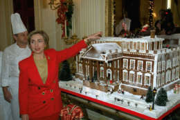 First lady Hillary Rodham Clinton points to a gingerbread house during a tour of the White House Christmas decorations, Monday Dec. 6, 1993.  Showcasing the "best of America," Mrs. Clinton unveiled the decorations,  a cozy display of crafts, trees and "funky and down to earth" ornaments.  White House head pastry chef Roland Mesnier is at left.  (AP Photo/Doug Mills)