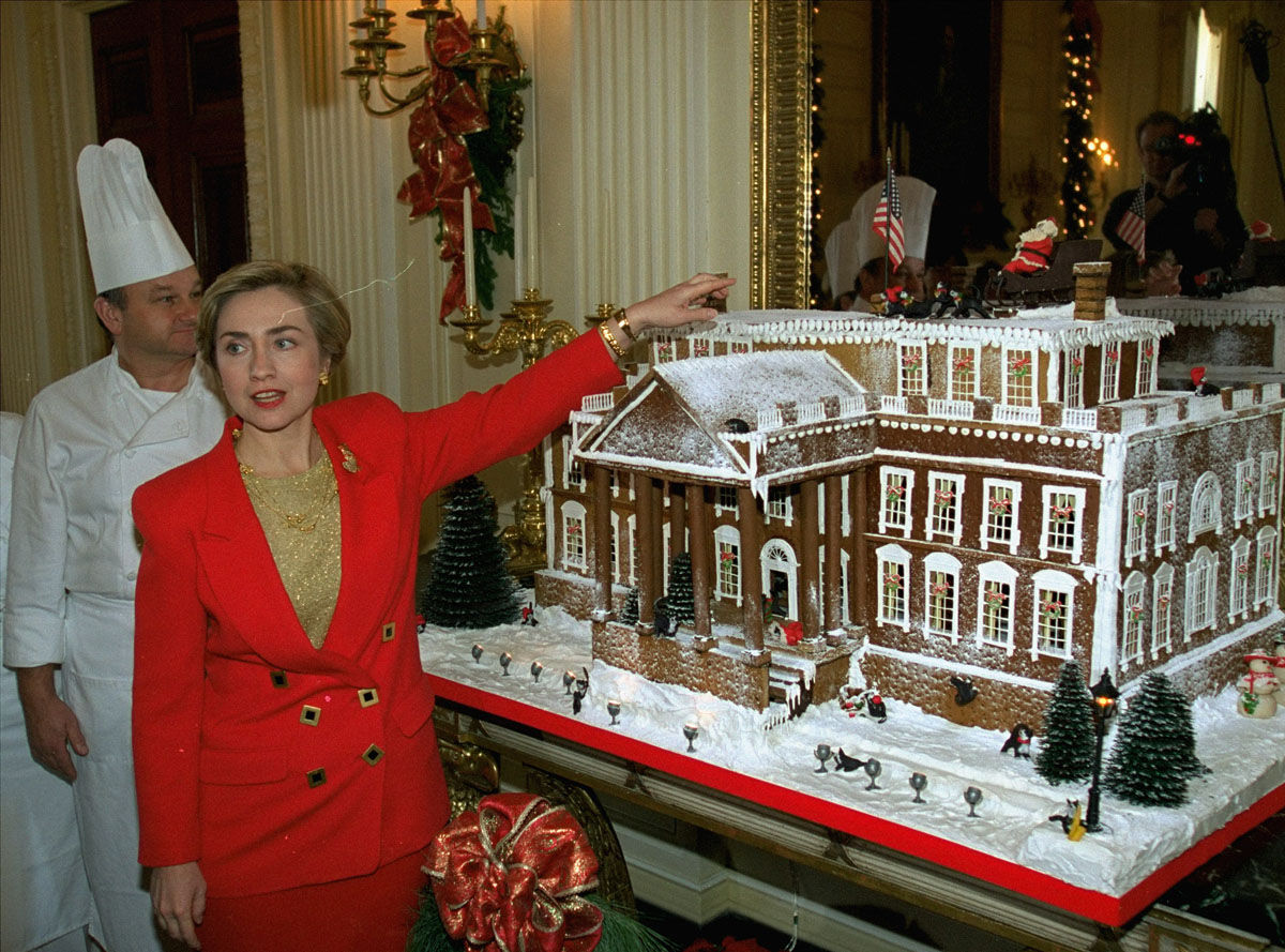 First lady Hillary Rodham Clinton points to a gingerbread house during a tour of the White House Christmas decorations, Monday Dec. 6, 1993.  Showcasing the "best of America," Mrs. Clinton unveiled the decorations,  a cozy display of crafts, trees and "funky and down to earth" ornaments.  White House head pastry chef Roland Mesnier is at left.  (AP Photo/Doug Mills)
