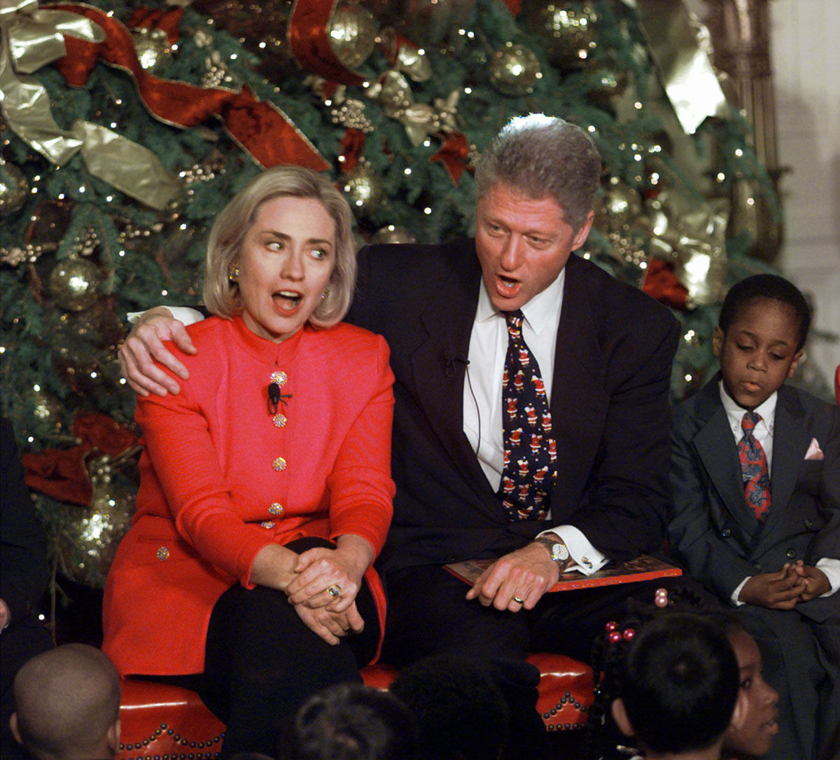 President and Mrs. Clinton sing Christmas carols in the East Room of the White House, Thursday, Dec. 18, 1997, while entertaining children from Washington. For the fifth year, the president and Mrs. Clinton met a group of children and the president read "'Twas the Night Before Christmas." Jelani Irby, a second-grader from Washington's Brightwood Elementary School sits at right. (AP Photo/Ron Edmonds)