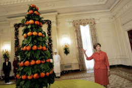First lady Laura Bush talks about a centerpiece, made of fresh tangerines and lemons leaves in the East Room of the White House Wednesday, Nov. 30, 2005 during a tour of the holiday decorations. With table centerpieces of fresh tangerines and lemon leaves, and Christmas trees decorated with real roses and lilacs, the White House is taking a fresh and natural approach to the 2005 holiday season. (AP Photo/Pablo Martinez Monsivais)