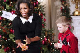 First lady Michelle Obama shows a gingerbread cookie she decorated with children from military families, in the State Dining Room of the White House in Washington, Wednesday, Nov. 30, 2011, as the Christmas holiday decorations, whose theme is "Shine, Give, Share" were previewed. (AP Photo/Charles Dharapak)