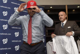 New Washington Nationals manager Dave Martinez, left, puts on his baseball cap as general manager Mike Rizzo, right, holds his jersey during a baseball press conference, Thursday, Nov. 2, 2017, in Washington. (AP Photo/Nick Wass)