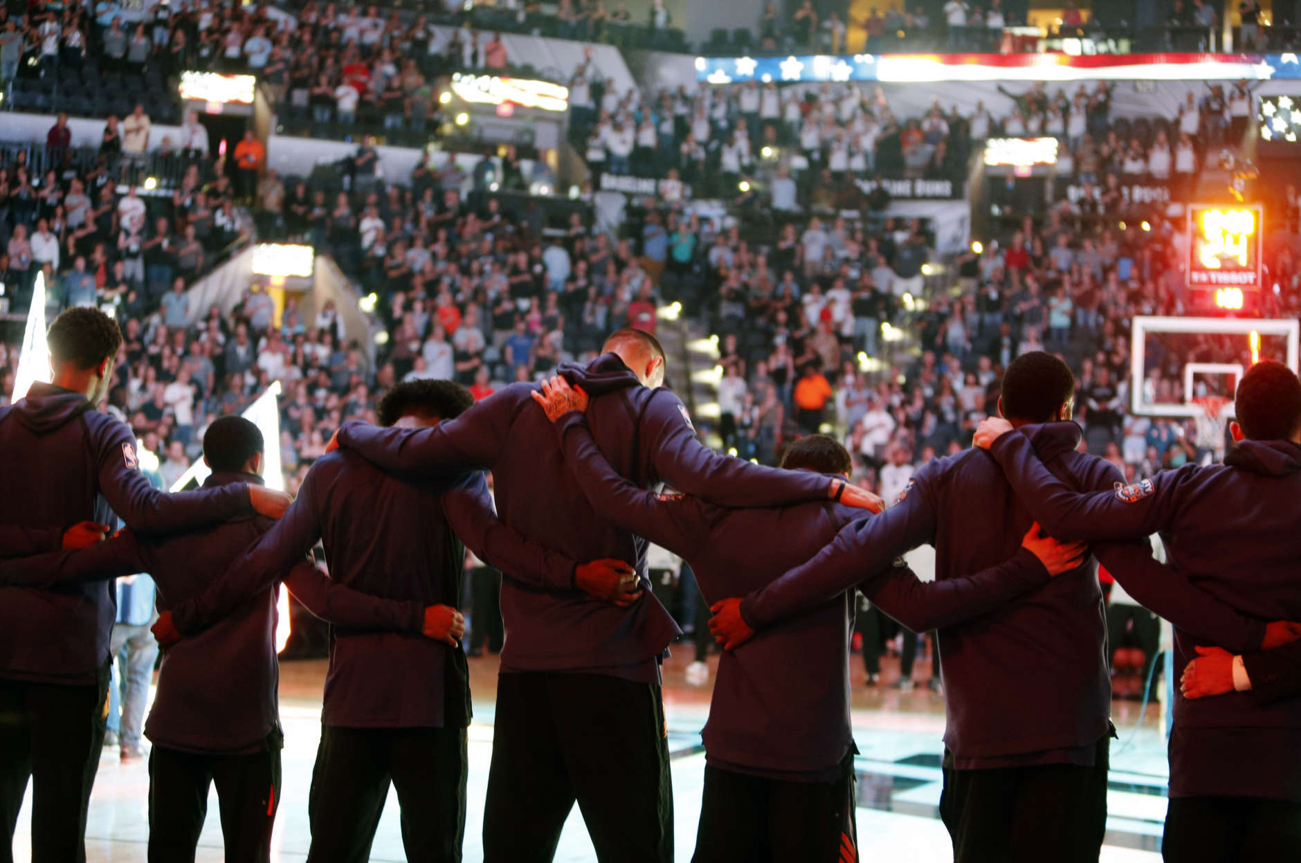 Members of the Phoenix Suns stand arm-in-arm during a moment of silence for the victims of a deadly church shooting in Texas before an NBA basketball team against the San Antonio Spurs, Sunday, Nov. 5, 2017 in San Antonio. (AP Photo/Ronald Cortes)