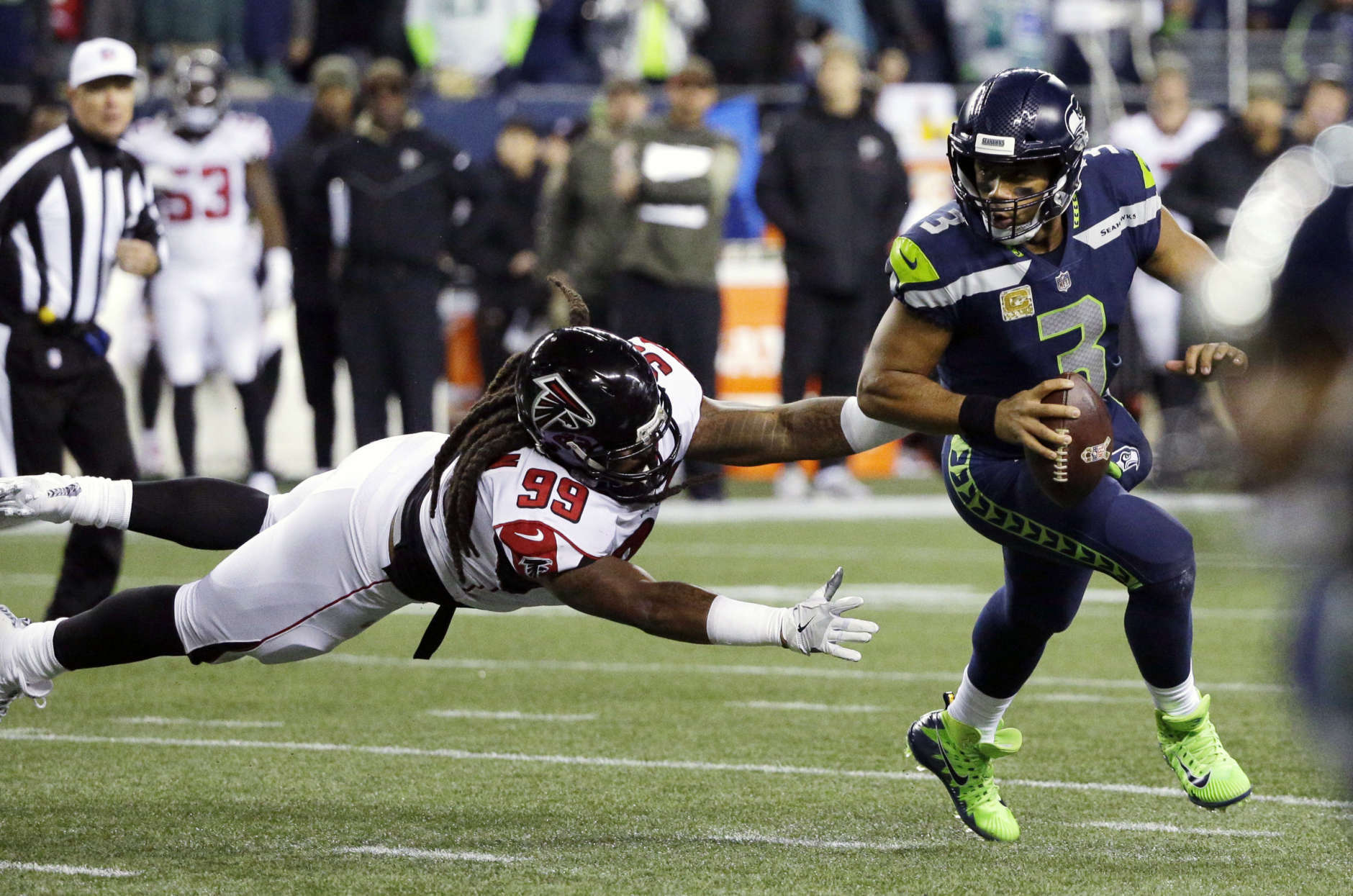 Seattle Seahawks quarterback Russell Wilson (3) scrambles away from a diving Atlanta Falcons defensive end Adrian Clayborn (99) in the first half of an NFL football game, Monday, Nov. 20, 2017, in Seattle. (AP Photo/Ted S. Warren)
