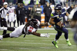 Seattle Seahawks quarterback Russell Wilson (3) scrambles away from a diving Atlanta Falcons defensive end Adrian Clayborn (99) in the first half of an NFL football game, Monday, Nov. 20, 2017, in Seattle. (AP Photo/Ted S. Warren)