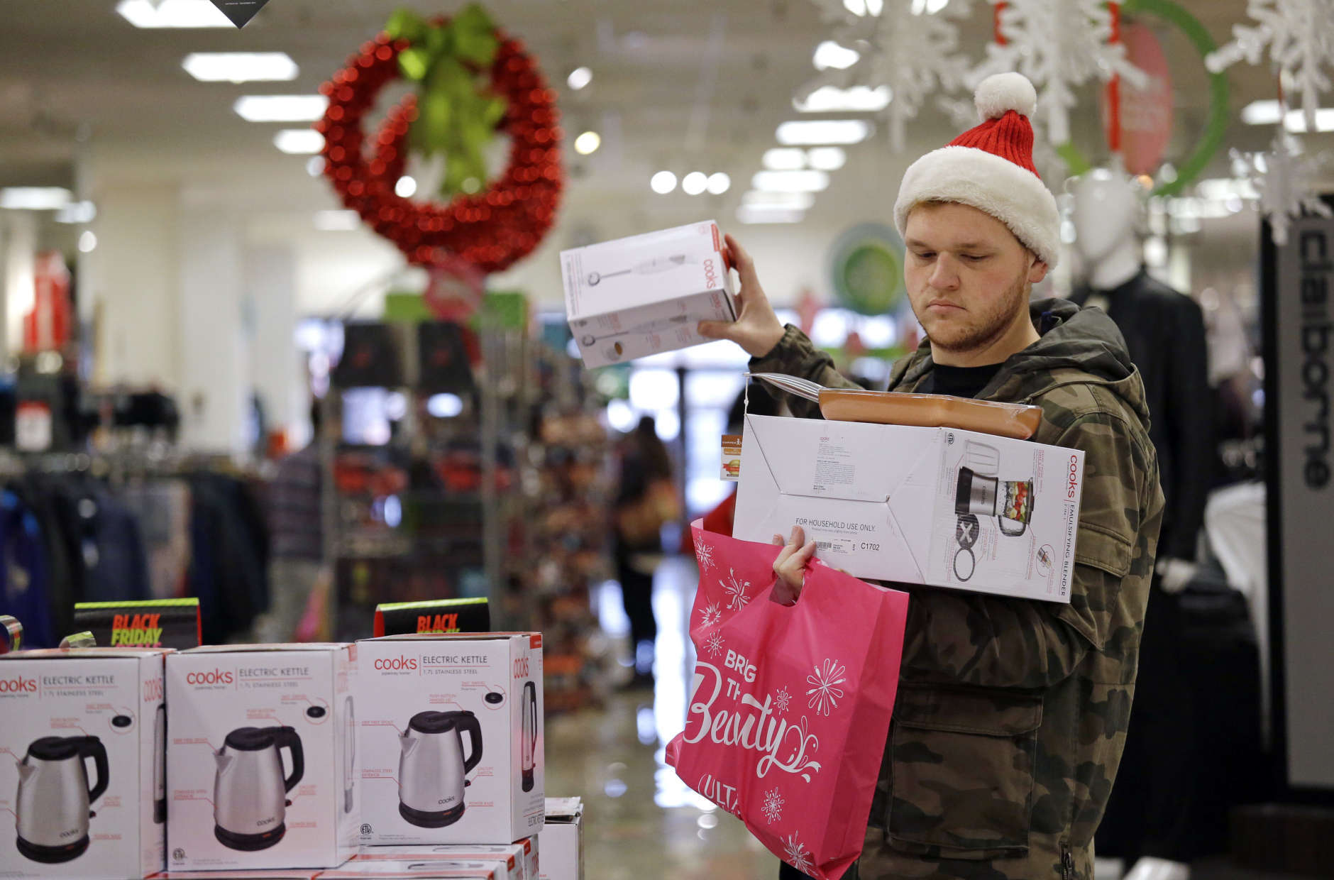 Joey Ellis adds to his armful of items while shopping for deals at a J.C. Penney store, Friday, Nov. 24, 2017, in Seattle. Black Friday has morphed from a single day when people got up early to score doorbusters into a whole season of deals, so shoppers may feel less need to be out. (AP Photo/Elaine Thompson)