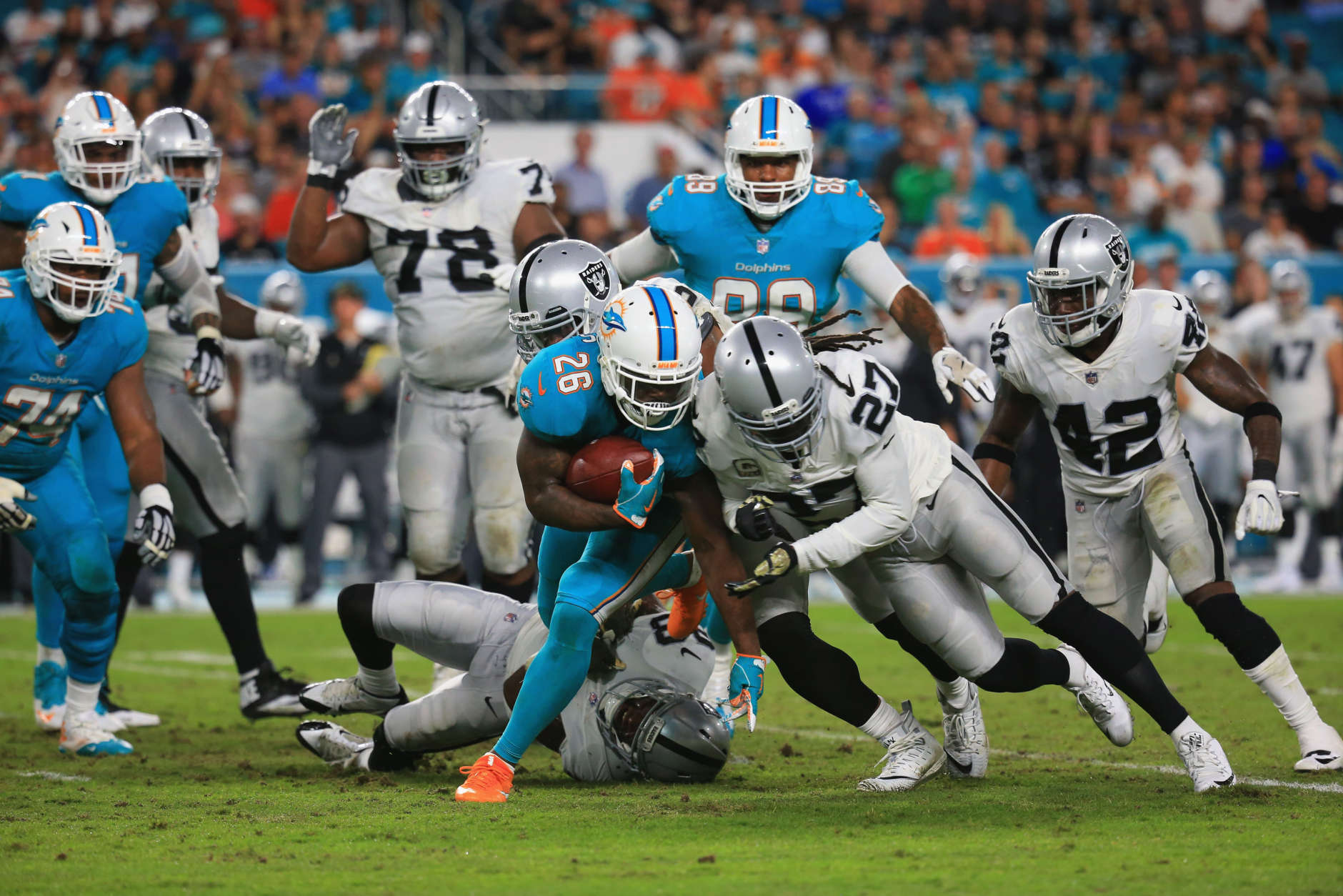 MIAMI GARDENS, FL - NOVEMBER 05: Running back Damien Williams #26 of the Miami Dolphins is tackled by free safety Reggie Nelson #27 of the Oakland Raiders at Hard Rock Stadium on November 5, 2017 in Miami Gardens, Florida.  (Photo by Chris Trotman/Getty Images)