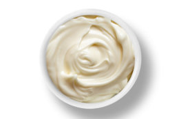 A small bowl of Mayonnaise isolated on a white background top down view from above