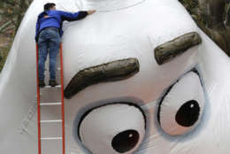 A man makes some adjustment on a large balloon being inflated for the Thanksgiving Day parade in New York, Wednesday, Nov. 22, 2017. Sand-filled sanitation trucks and police sharpshooters will mix with glittering floats and giant balloons at a Macy's Thanksgiving Day Parade that comes in a year of terrible mass shootings and not even a month after a deadly truck attack in lower Manhattan. (AP Photo/Seth Wenig)