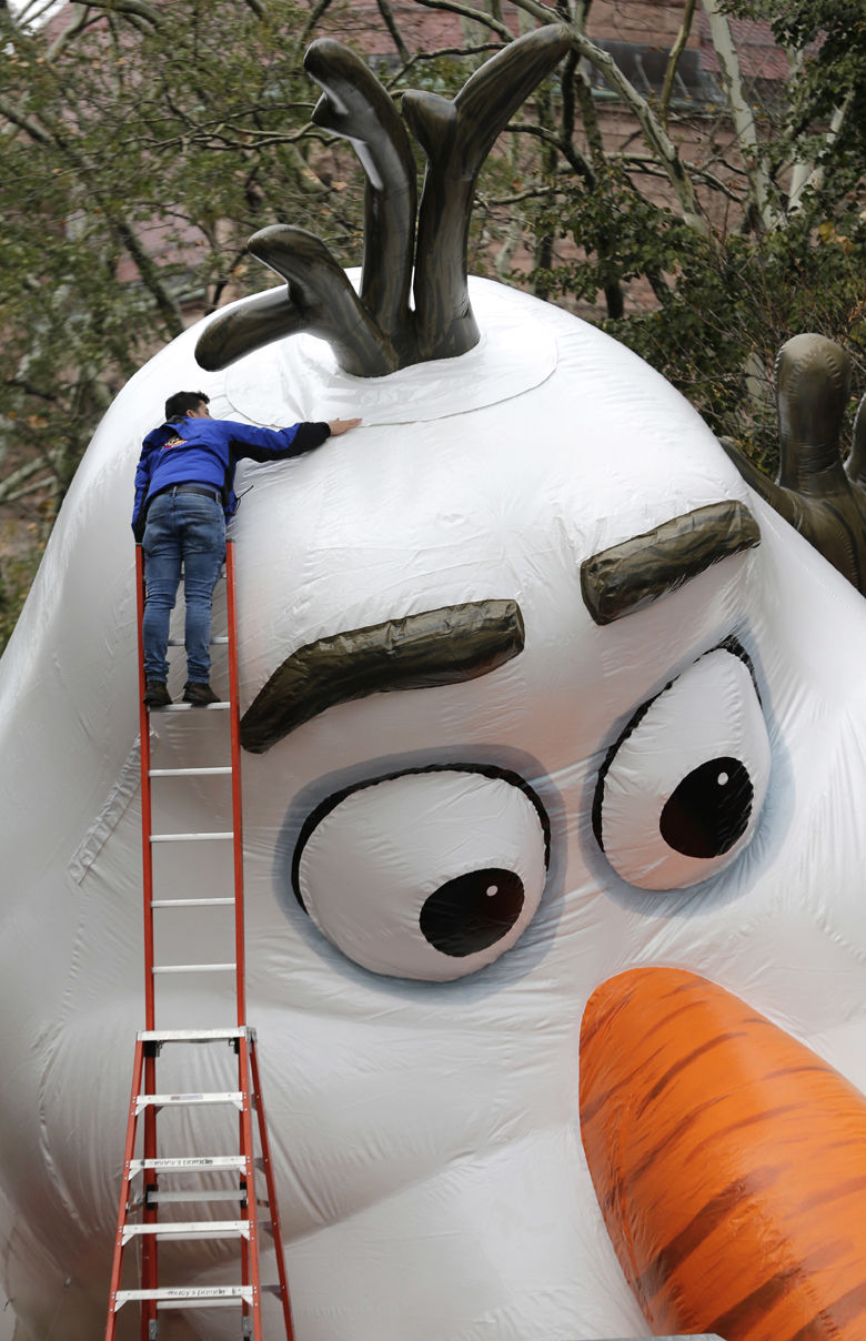 A man makes some adjustment on a large balloon being inflated for the Thanksgiving Day parade in New York, Wednesday, Nov. 22, 2017. Sand-filled sanitation trucks and police sharpshooters will mix with glittering floats and giant balloons at a Macy's Thanksgiving Day Parade that comes in a year of terrible mass shootings and not even a month after a deadly truck attack in lower Manhattan. (AP Photo/Seth Wenig)