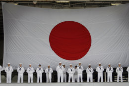 U.S. navy sailors stand at attention with the backdrop of Japanese national flag as their ship U.S. aircraft carrier USS Kitty Hawk leaves  Yokosuka Naval Base, Japan, Wednesday, May 28, 2008. The ship left  Japan for the last time for retirement. (AP Photo/Junji Kurokawa)