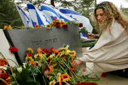 An Israeli woman lays a flower at the grave of late Israeli Prime Minister Yitzhak Rabin during a memorial at Mount Hertzl cemetery in Jerusalem, Friday, Nov. 4, 2005. On the 10-year anniversary of the assassination of Prime Minister Yitzhak Rabin, the official who was responsible for the Israeli leader's security is calling for a new investigation into the killing. (AP Photo/Kevin Frayer)
