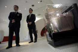 Kazuo Sumimiya, left, manager of a showroom of Lixil, the firm that owns Japan's toilet maker Inax, and Lixil PR person Shintaro Kaai stand near a toilet decorated with 72,000 pieces of crystal from Swarovski AG of Austria at the showroom in Tokyo Tuesday, Dec. 13, 2011. The toilet, valued at 10 million yen (US$128,000) by Lixil although it is not for sale, is on display until Dec. 28. (AP Photo/Junji Kurokawa)