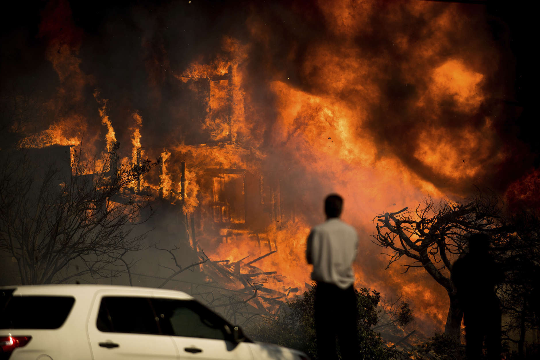 A man watches flames consume a residence as a wildfire rages in Ventura, Calif., Tuesday, Dec. 5, 2017. Ferocious winds in Southern California have whipped up explosive wildfires, burning a psychiatric hospital and scores of other structures. (AP Photo/Noah Berger)