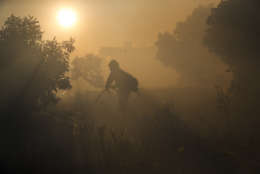 A firefighter pulls a water hose as a wildfires continues to burn Tuesday, Dec. 5, 2017, in Santa Paula, Calif. Raked by ferocious Santa Ana winds, explosive wildfires northwest of Los Angeles and in the city's foothills burned a psychiatric hospital and scores of homes and other structures Tuesday and forced the evacuation of tens of thousands of people. (AP Photo/Jae C. Hong)