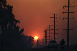 The sun is seen through thick smoke generated by a wildfire Tuesday, Dec. 5, 2017, in Santa Paula, Calif. Raked by ferocious Santa Ana winds, explosive wildfires northwest of Los Angeles and in the city's foothills burned a psychiatric hospital and scores of homes and other structures Tuesday and forced the evacuation of tens of thousands of people. (AP Photo/Jae C. Hong)