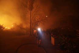 Fire crews prepare to defend a home as a wildfire advances Thursday, Dec. 7, 2017, in Bonsall, Calif. The wind-swept blazes have forced tens of thousands of evacuations and destroyed dozens of homes in Southern California. (AP Photo/Gregory Bull)