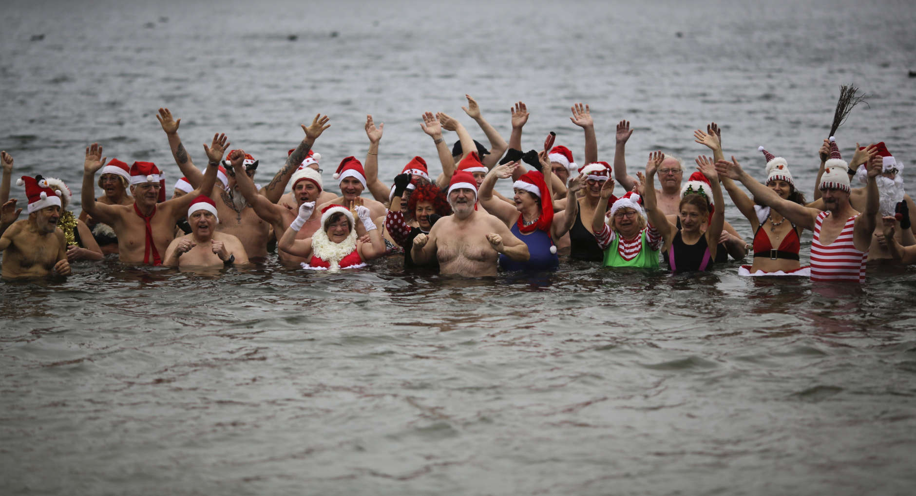 Members of the winter and ice swimming club 'Seehunde Berlin', (Berlin Seals), wearing Christmas themed hats, celebrate during the annual Christmas swim on Christmas Day, at the Oranke Lake in Berlin, Monday, Dec. 25, 2017. (AP Photo/Markus Schreiber)