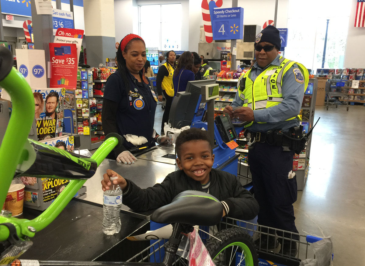 Haiden, 6, is a happy customer shopping with D.C. Police Officer Michael Fisher. (WTOP/Kristi King)
