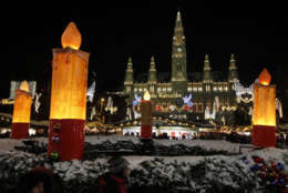 People walk past the festively lit up Viennese city hall with the Christmas tree and the Viennese Christmas Market in front in Vienna, Austria, on Sunday, Dec. 19, 2010.  (AP Photo/Ronald Zak)