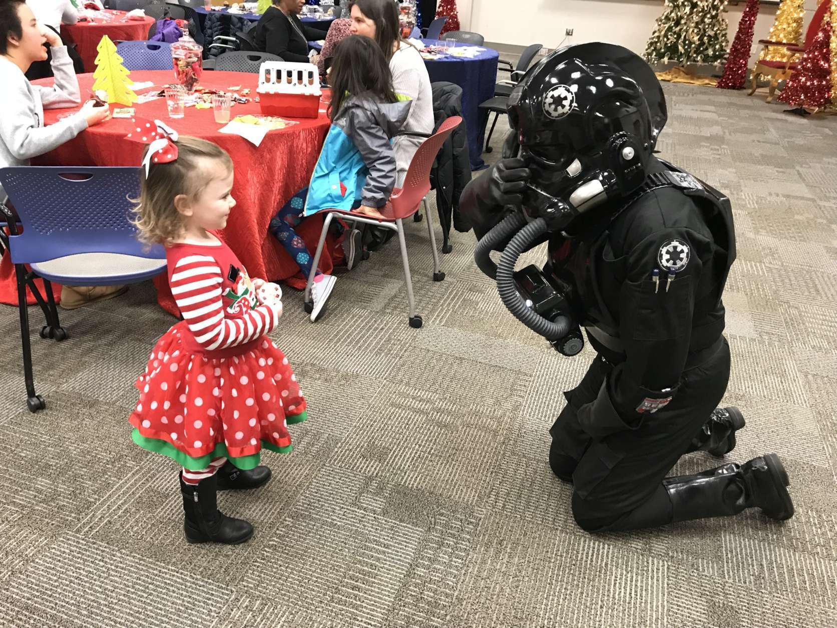 A TIE fighter pilot plays peekaboo with a little girl. He may look like bad guy, but he’s soft on the inside. (WTOP/Michelle Basch)