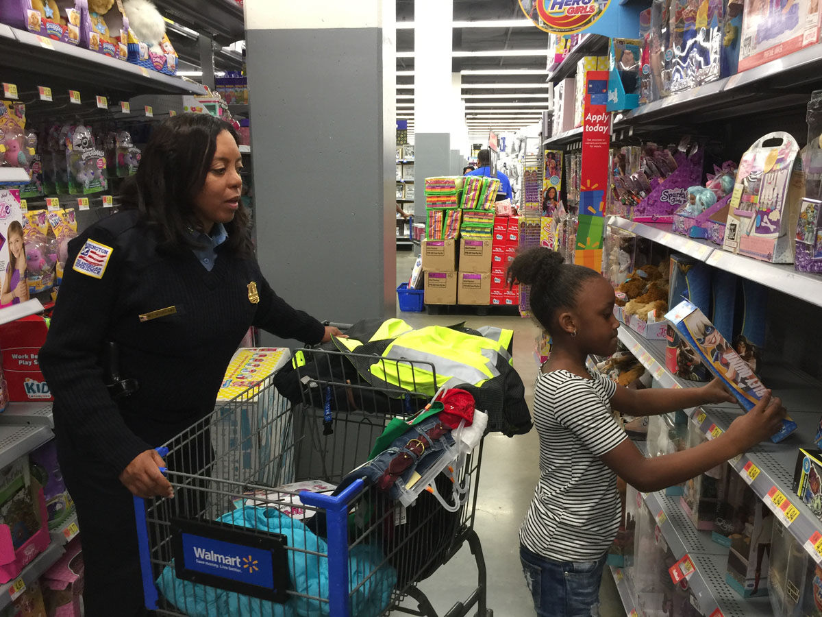 She's reaching for a doll, but 6-year-old Anyair, pictured with Sgt. Melicia Woodland, said she really likes dresses. She bought two. (WTOP/Kristi King)