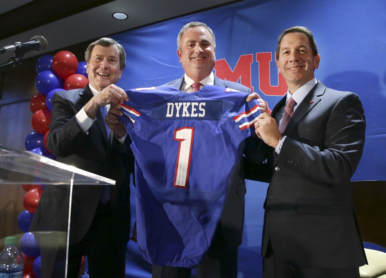New SMU head football coach Sonny Dykes, center, holds up a jersey with university president Gerald Turner, left, and athletic director Rick Hart after Dykes' introduction in Dallas, Tuesday, Dec. 12, 2017. SMU hired the former California and Louisiana Tech coach as its new coach, replacing one Texan with reputation for directing potent offenses for another. Dykes will replace Chad Morris, who left SMU last week to become Arkansas' coach.(AP Photo/LM Otero)