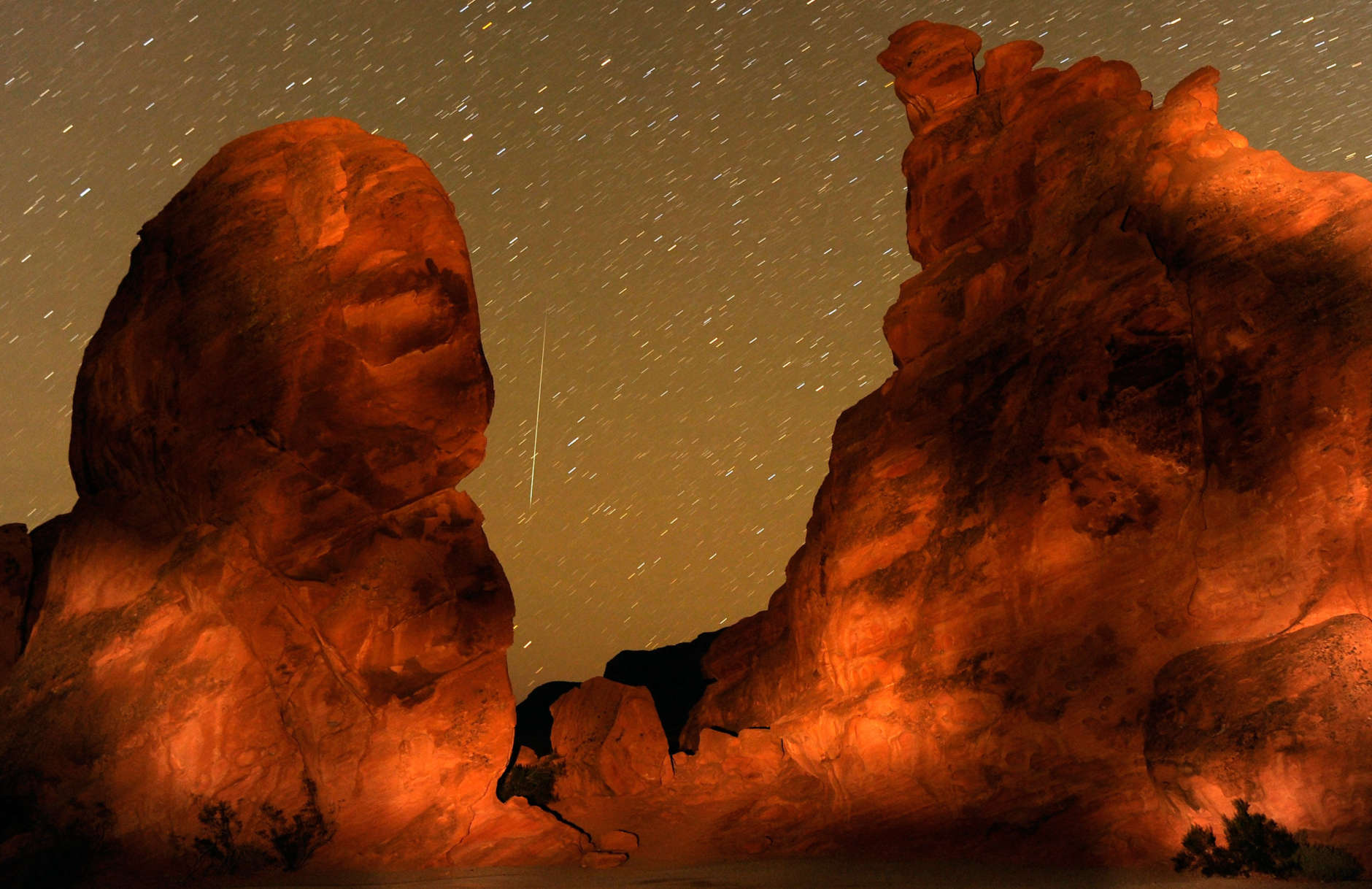 A Geminid meteor streaks between peaks of the Seven Sisters rock formation early December 14, 2010 in the Valley of Fire State Park in Nevada. The meteor display, known as the Geminid meteor shower because it appears to radiate from the constellation Gemini, is thought to be the result of debris cast off from an asteroid-like object called 3200 Phaethon. The shower is visible every December.  (Photo by Ethan Miller/Getty Images)