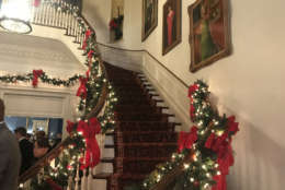 The grand entrance hall was decorated with greenery and red bows sweeping up the grand staircase. (WTOP/Dick Uliano)